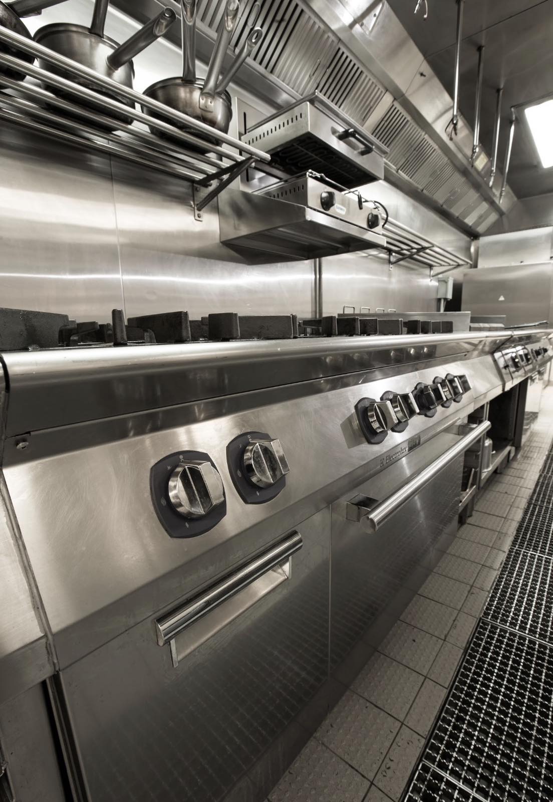 Commercial cooking line with stainless steel equipment and ventilation hood