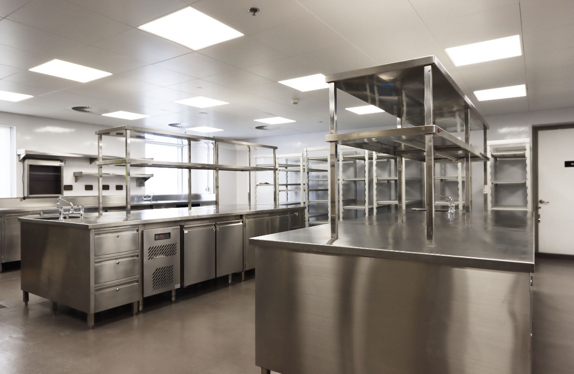 Commercial kitchen with stainless steel preparation counters and shelving