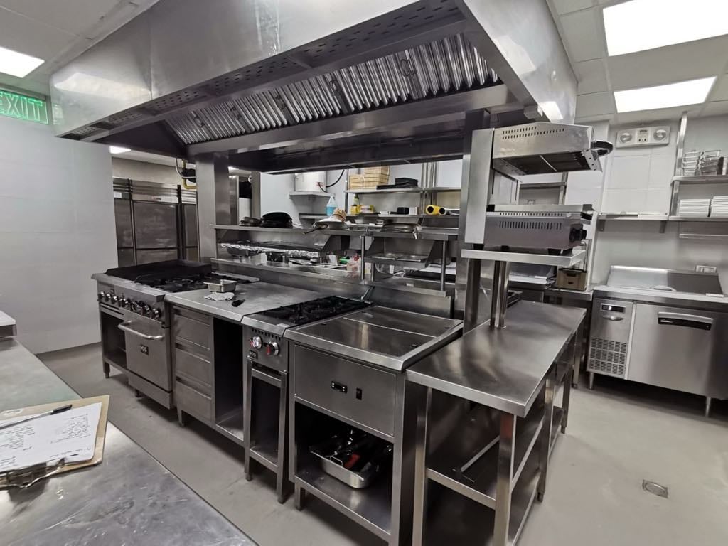 TRES Restaurant OPUS Mall kitchen line with stainless cooking equipment and exhaust hood