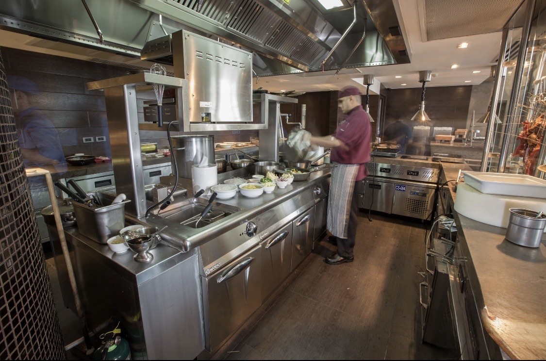 Commercial kitchen line with stainless foodservice equipment in operation.
